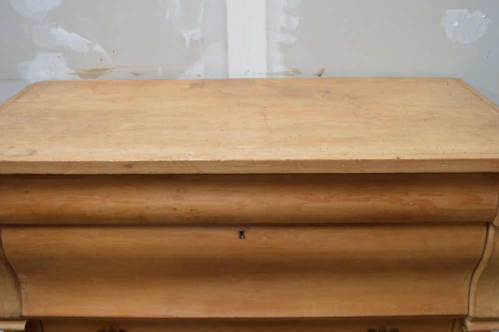 A Victorian pine chest of drawers featuring an ogee top drawer, turned side columns, brass handles, and bun feet. View II