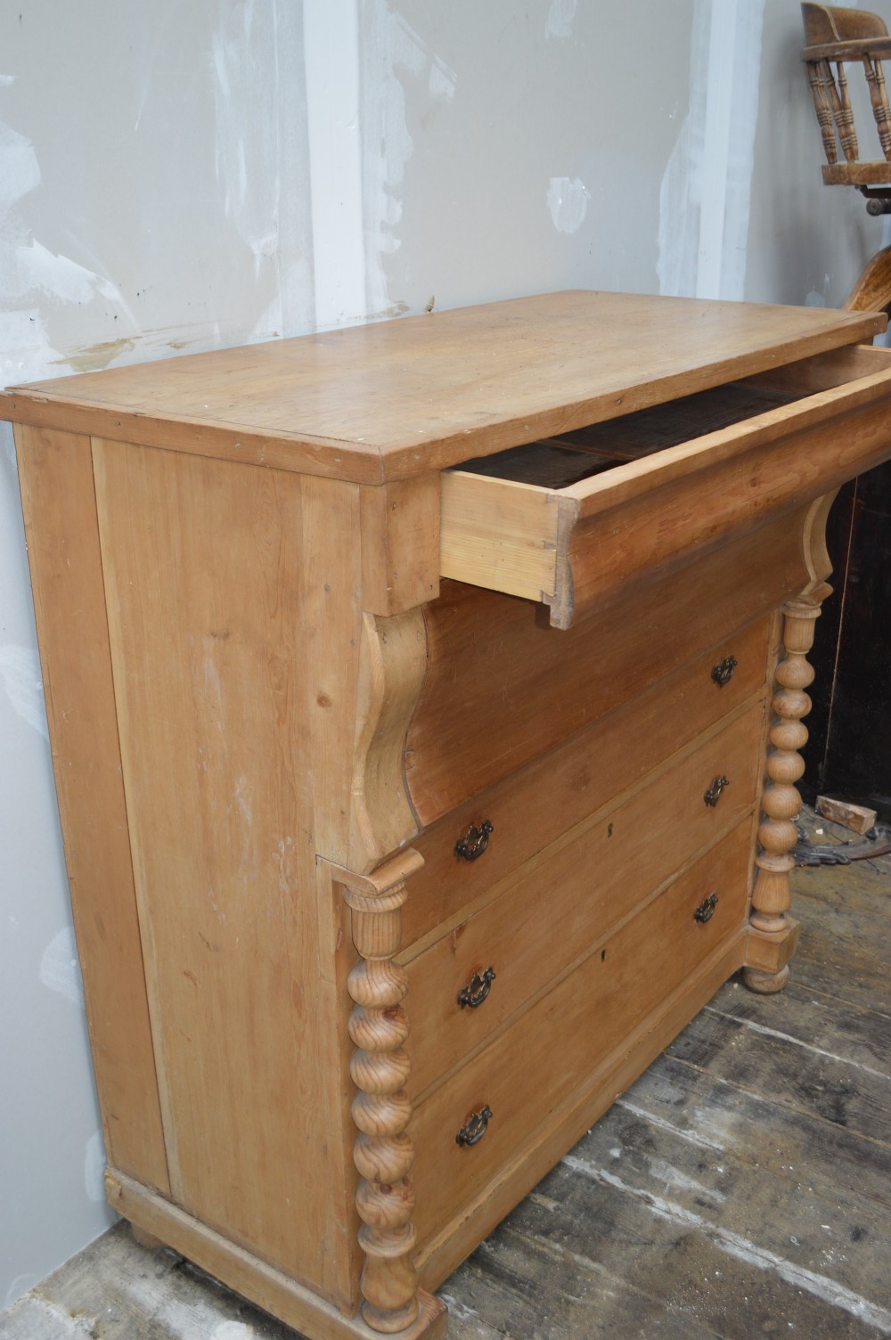 A Victorian pine chest of drawers featuring an ogee top drawer, turned side columns, brass handles, and bun feet. View III