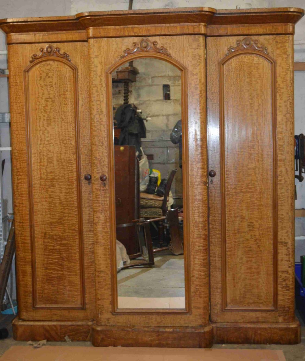 A Victorian Breakfront fiddleback Ash three door mirror wardrobe