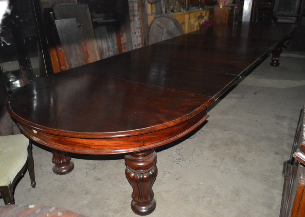 A large Victorian dark mahogany extending dining table featuring thick turned legs with a rounded tabletop. View VI