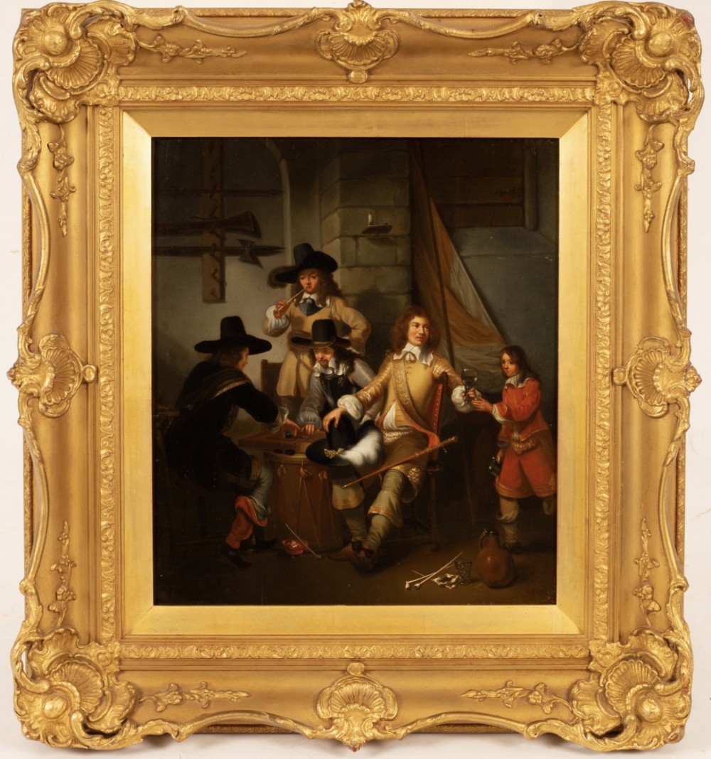 An oil painting depicting 17th-century figures seated around a table in an interior setting, housed within an ornate gilded frame.