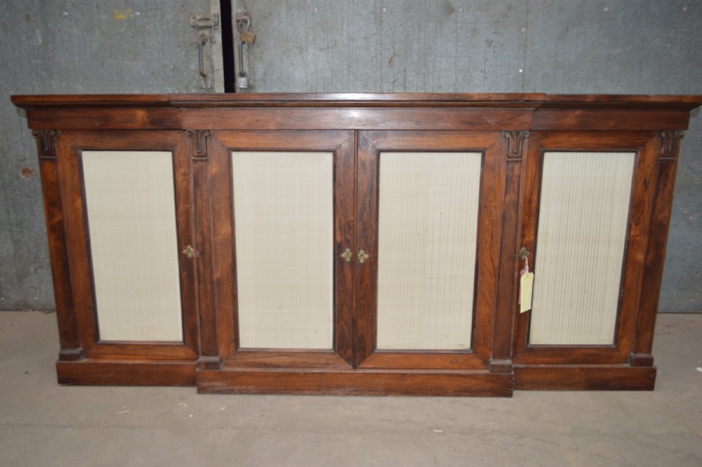 A Regency rosewood breakfront cabinet featuring four doors with pleated fabric panels and carved pilasters. View II