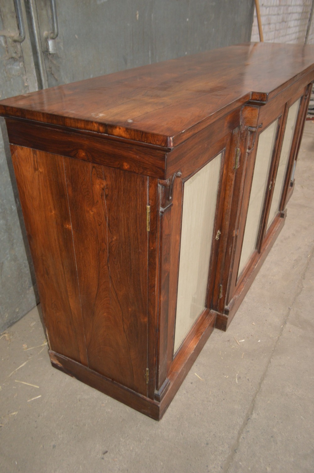 A Regency rosewood breakfront cabinet featuring four doors with pleated fabric panels and carved pilasters. View V