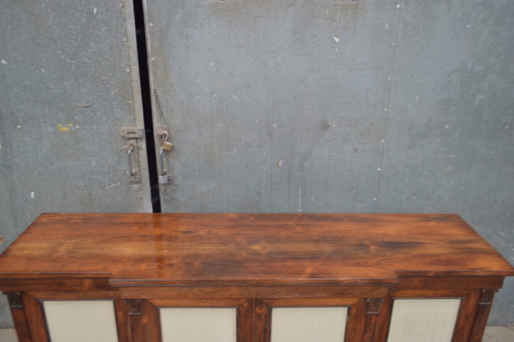 A Regency rosewood breakfront cabinet featuring four doors with pleated fabric panels and carved pilasters. View VII