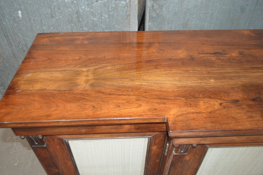 A Regency rosewood breakfront cabinet featuring four doors with pleated fabric panels and carved pilasters. View IX