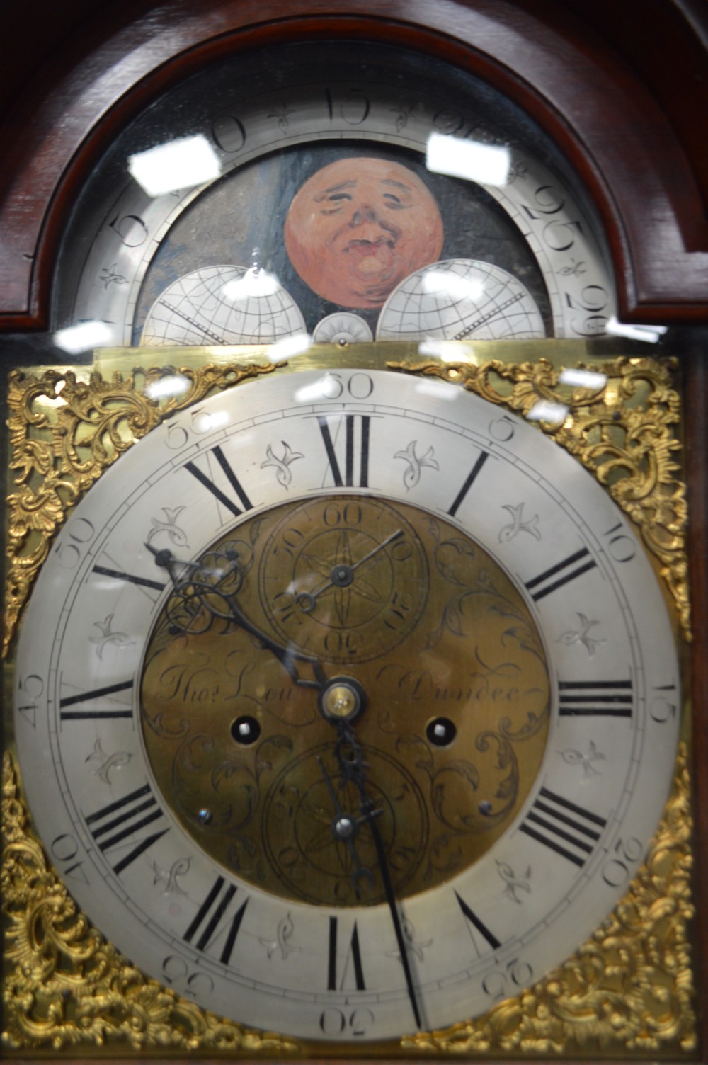 A tall Georgian mahogany longcase clock featuring an arched hood, a brass and spandrel dial with a moon phase disk, and an inlaid central door. View II