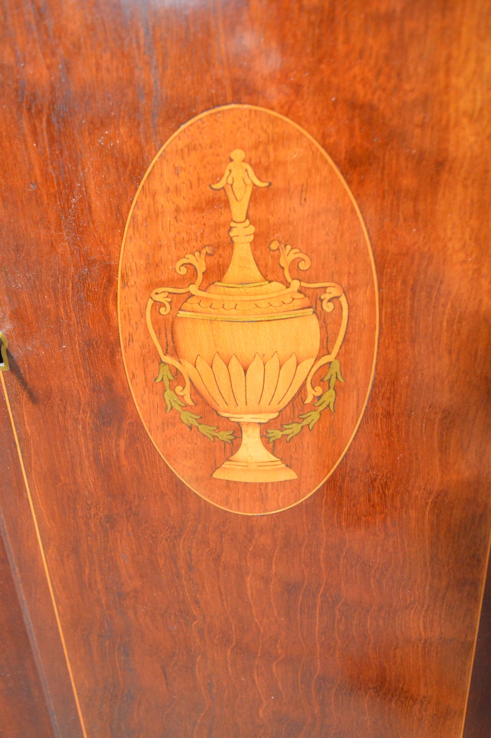 A tall Georgian mahogany longcase clock featuring an arched hood, a brass and spandrel dial with a moon phase disk, and an inlaid central door. View V