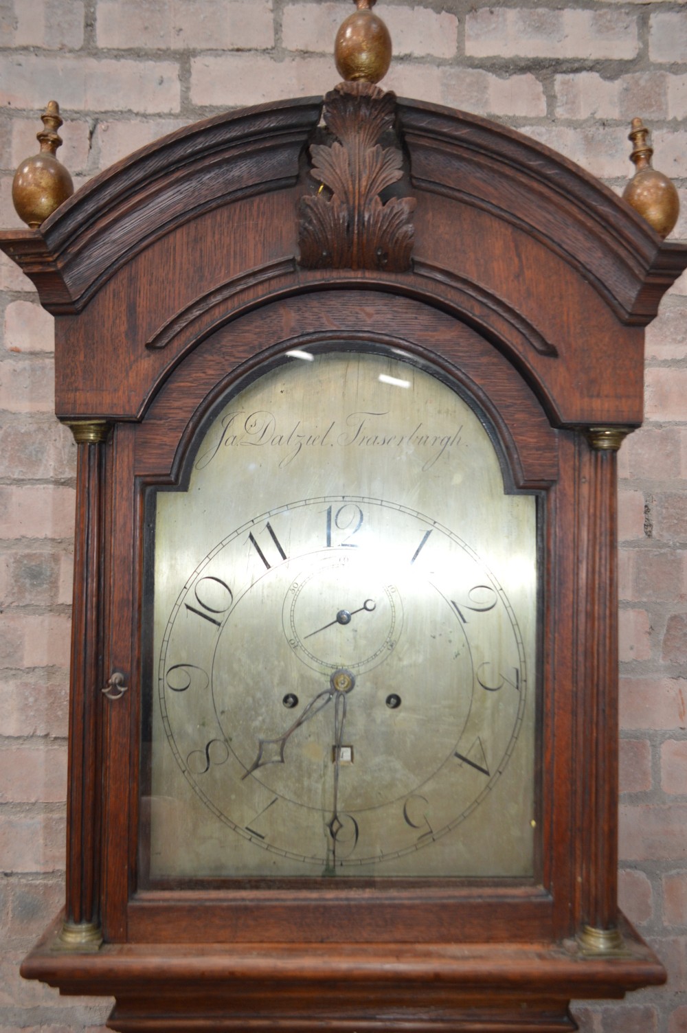 A late Victorian Scottish oak longcase clock with an arched hood, carved finials, and an arched painted dial. View II