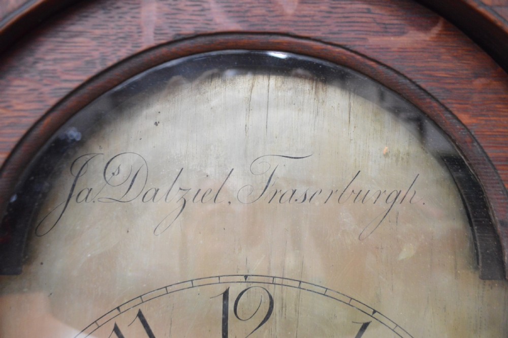 A late Victorian Scottish oak longcase clock with an arched hood, carved finials, and an arched painted dial. View III