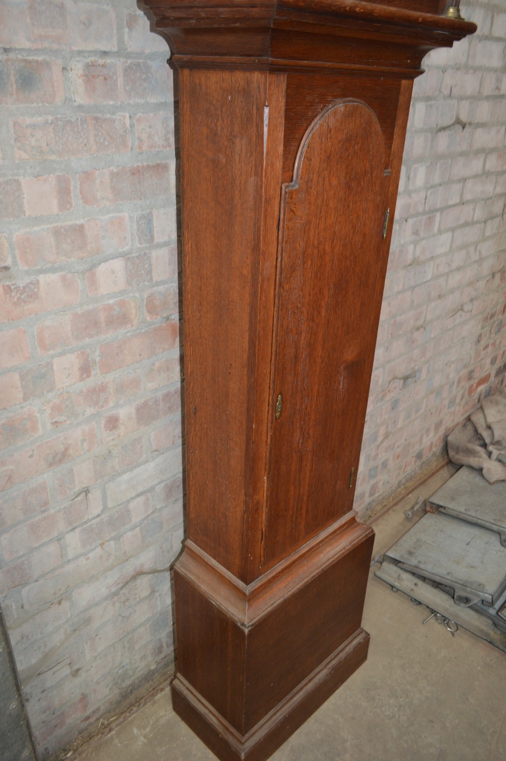 A late Victorian Scottish oak longcase clock with an arched hood, carved finials, and an arched painted dial. View VI
