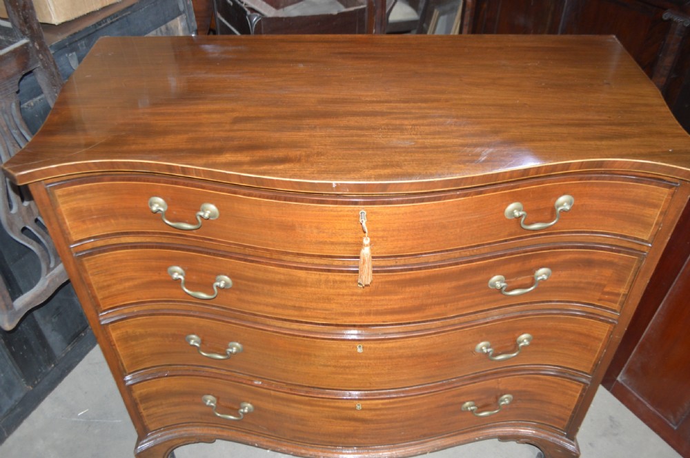 An 18th-century mahogany serpentine chest of drawers featuring four graduating drawers with brass handles and ogee bracket feet. View II