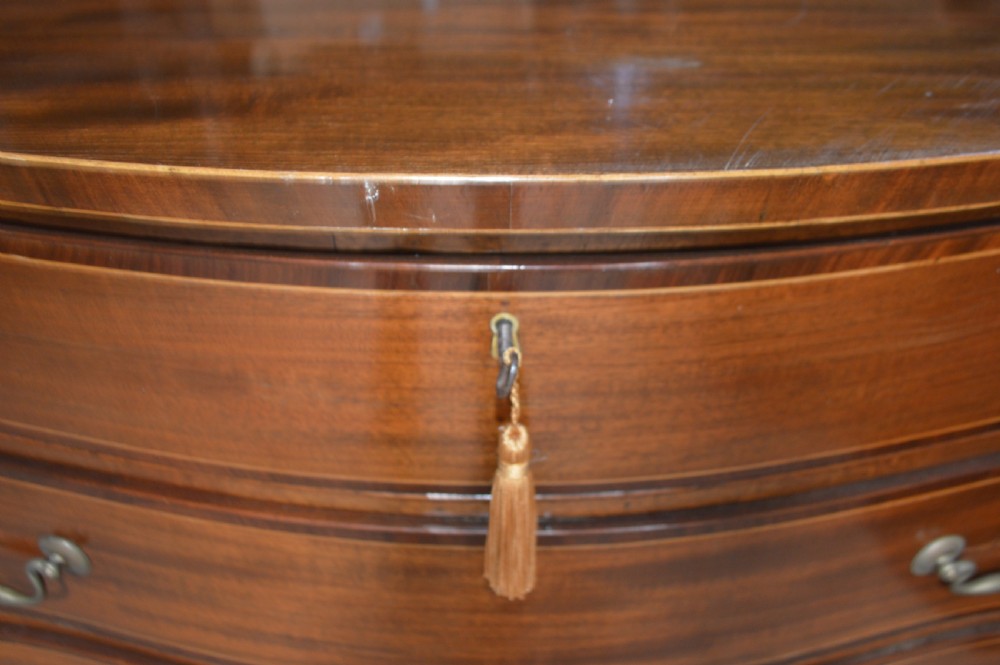 An 18th-century mahogany serpentine chest of drawers featuring four graduating drawers with brass handles and ogee bracket feet. View IV