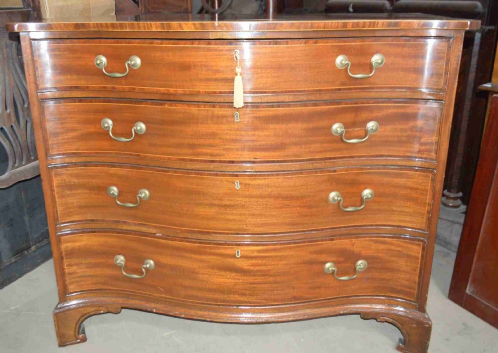An 18th-century mahogany serpentine chest of drawers featuring four graduating drawers with brass handles and ogee bracket feet.