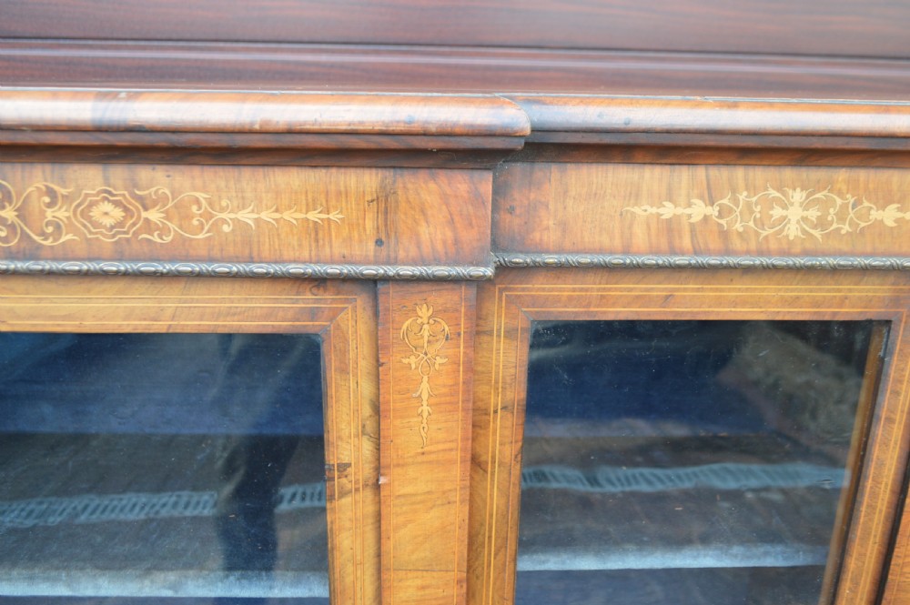 A low Victorian burr walnut breakfront bookcase featuring three glazed doors with floral marquetry inlays and decorative metal escutcheons. View V