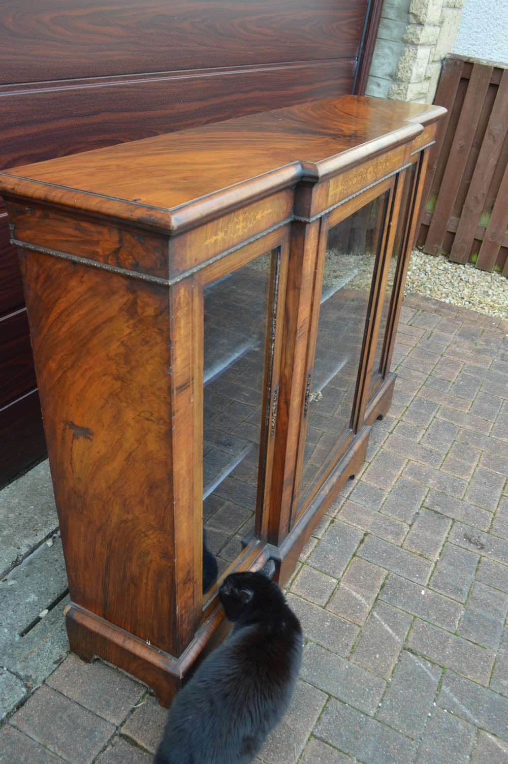 A low Victorian burr walnut breakfront bookcase featuring three glazed doors with floral marquetry inlays and decorative metal escutcheons. View VI