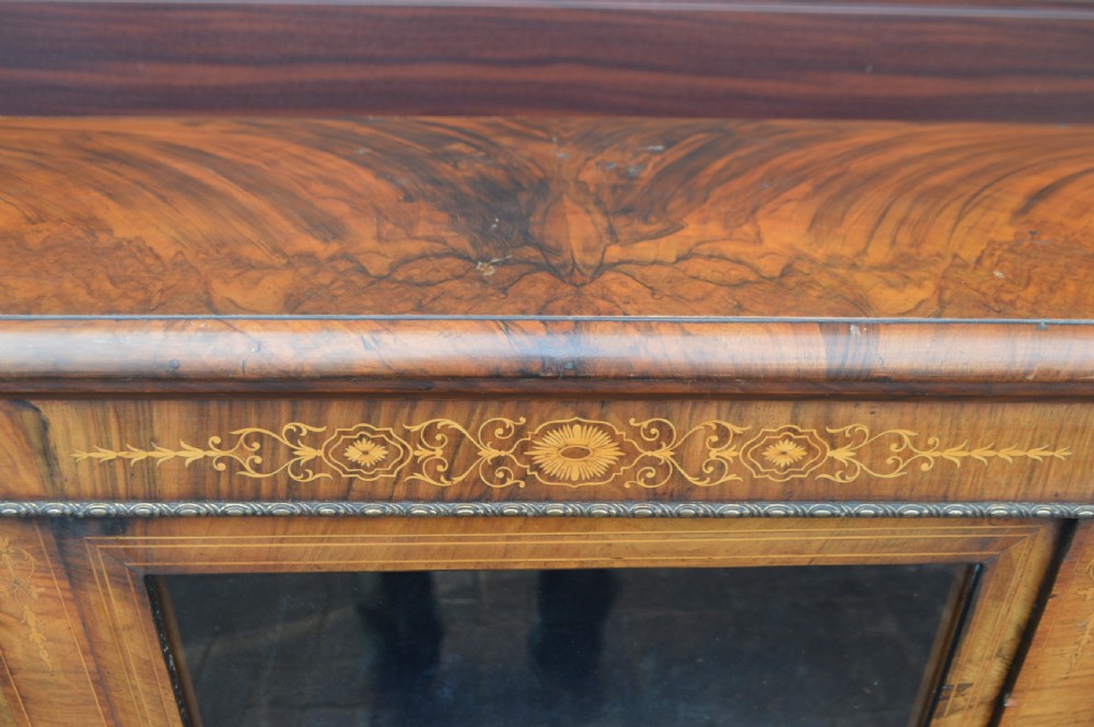 A low Victorian burr walnut breakfront bookcase featuring three glazed doors with floral marquetry inlays and decorative metal escutcheons. View VII