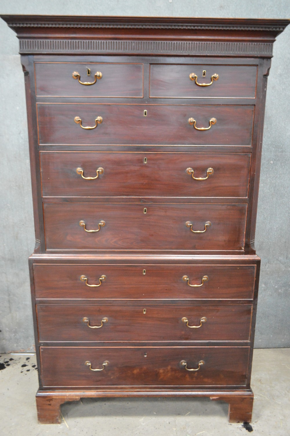 A tall Georgian mahogany chest on chest featuring two short over six long drawers with brass swan-neck handles and a dentil corniced top.