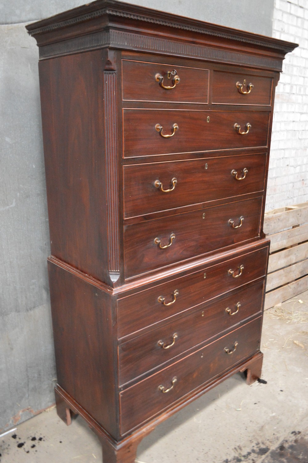 A tall Georgian mahogany chest on chest featuring two short over six long drawers with brass swan-neck handles and a dentil corniced top. View II
