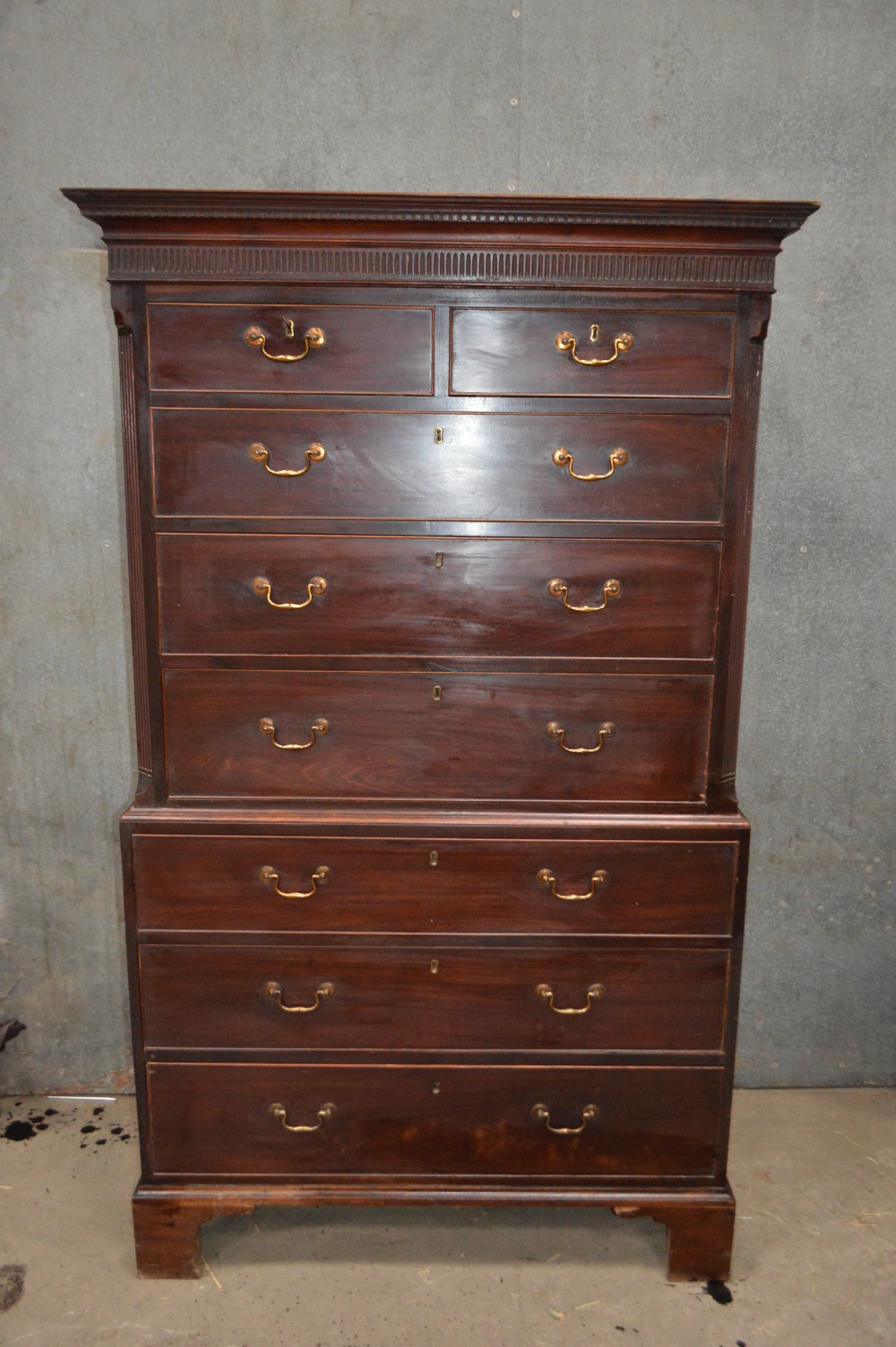 A tall Georgian mahogany chest on chest featuring two short over six long drawers with brass swan-neck handles and a dentil corniced top. View VI