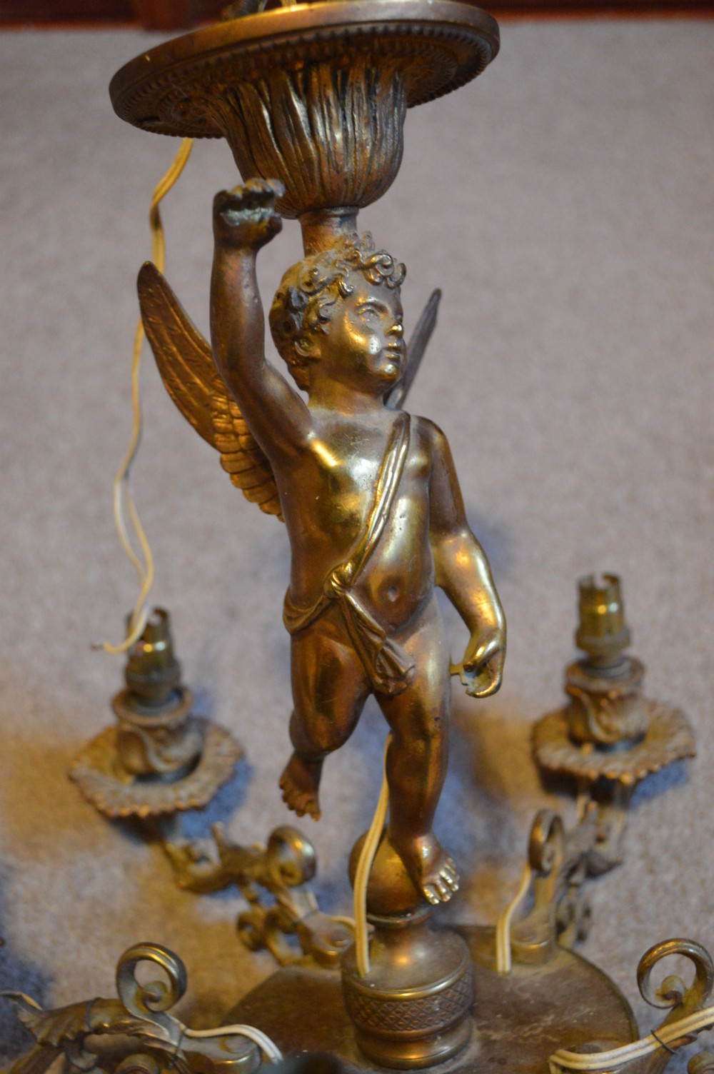 A nineteenth-century gilt metal chandelier featuring a central winged cherub supporting a column above five scrolling candelabra arms. View II