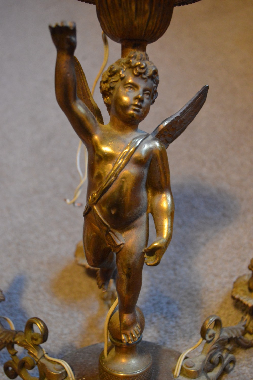 A nineteenth-century gilt metal chandelier featuring a central winged cherub supporting a column above five scrolling candelabra arms. View III