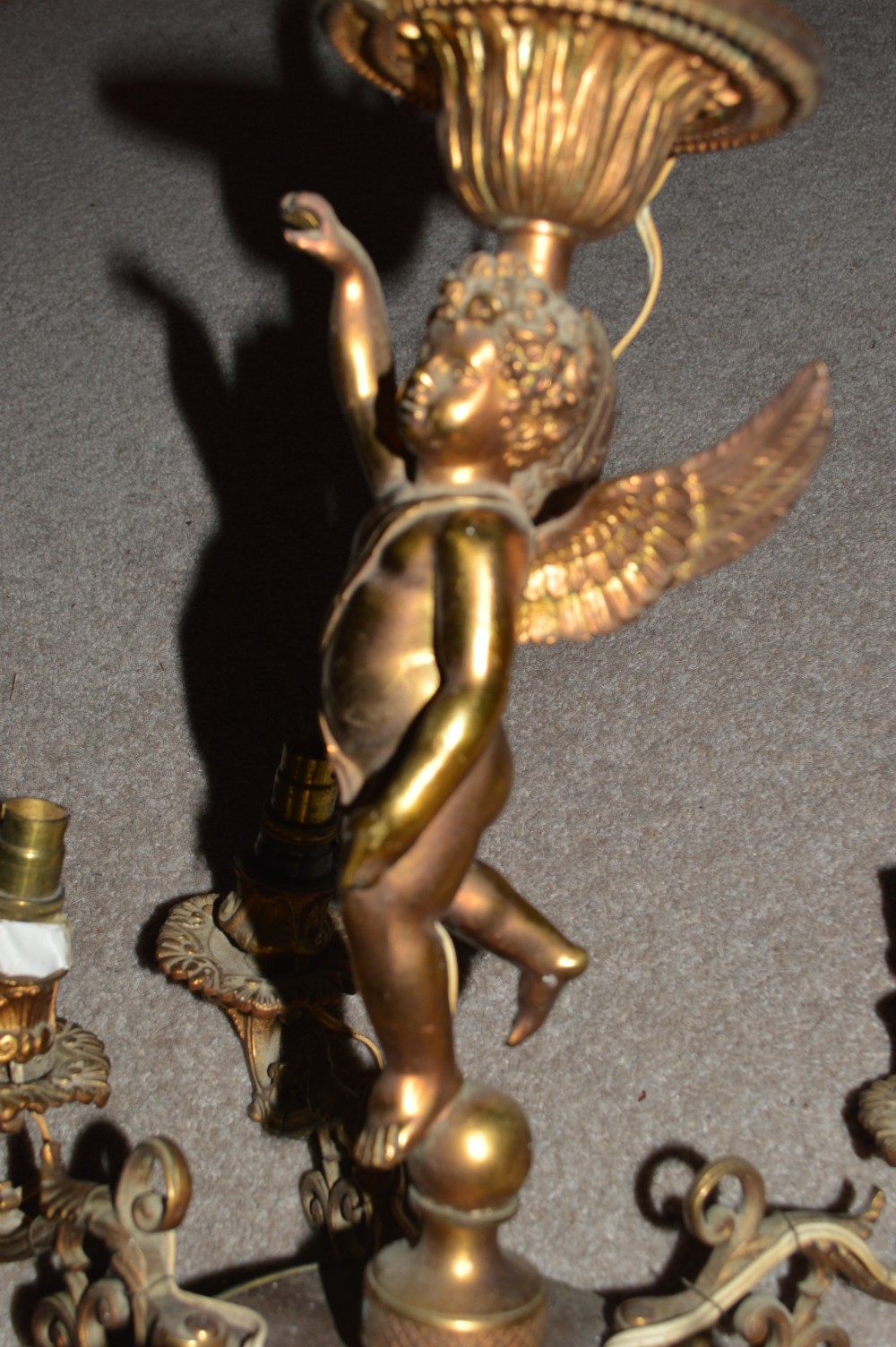 A nineteenth-century gilt metal chandelier featuring a central winged cherub supporting a column above five scrolling candelabra arms. View IV