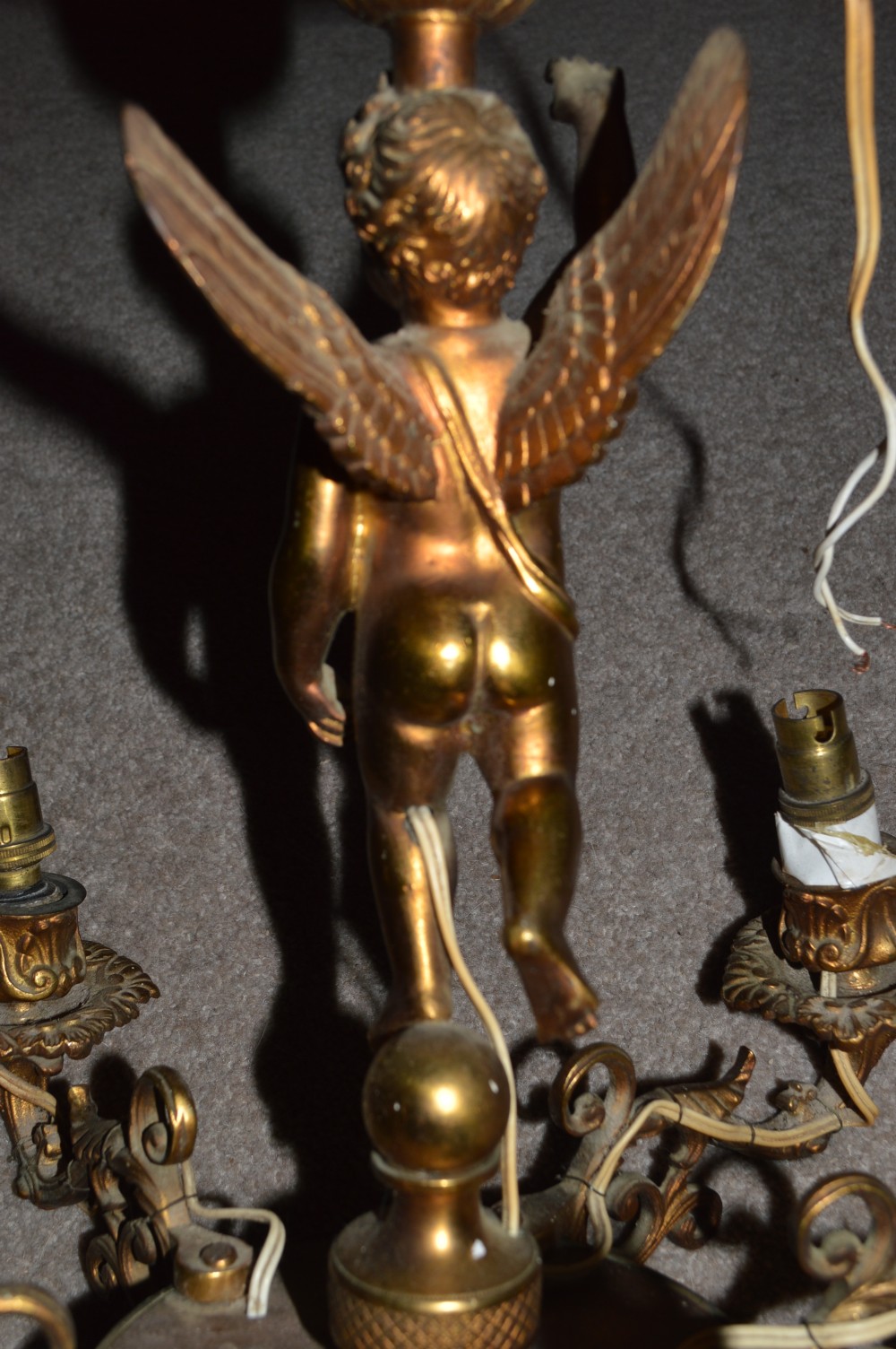 A nineteenth-century gilt metal chandelier featuring a central winged cherub supporting a column above five scrolling candelabra arms. View V