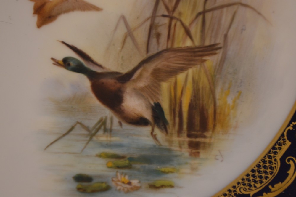 A circular Royal Worcester porcelain cabinet plate featuring a central hand-painted scene of game birds in flight surrounded by a dark cobalt blue rim with gold scrollwork gilding. View XIX