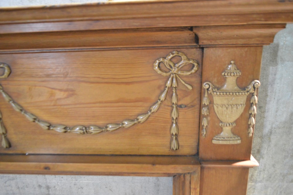 A Regency period pine fire surround featuring detailed gesso classical urns, draped swags, and fluted jambs. View III