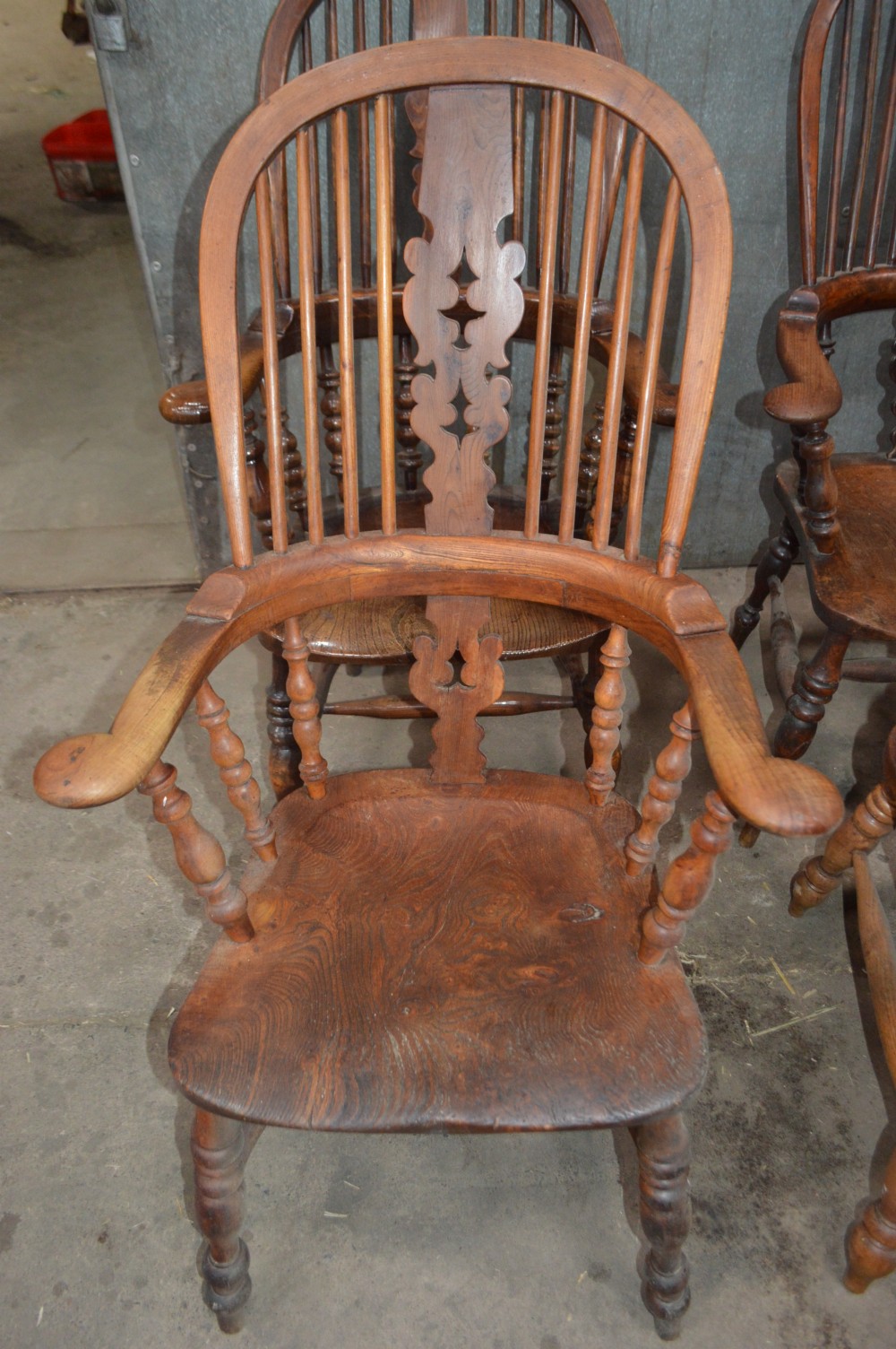 A set of six Victorian wooden Windsor armchairs featuring high hoop backs, central decorative splats, pad arms, and turned legs. View II