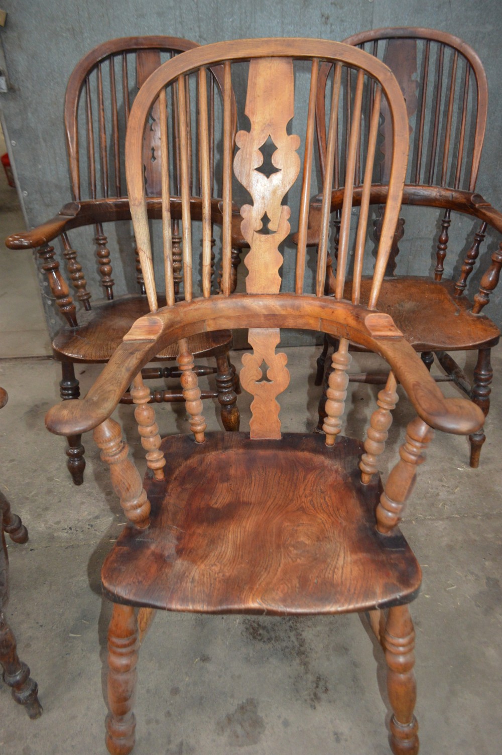 A set of six Victorian wooden Windsor armchairs featuring high hoop backs, central decorative splats, pad arms, and turned legs. View V
