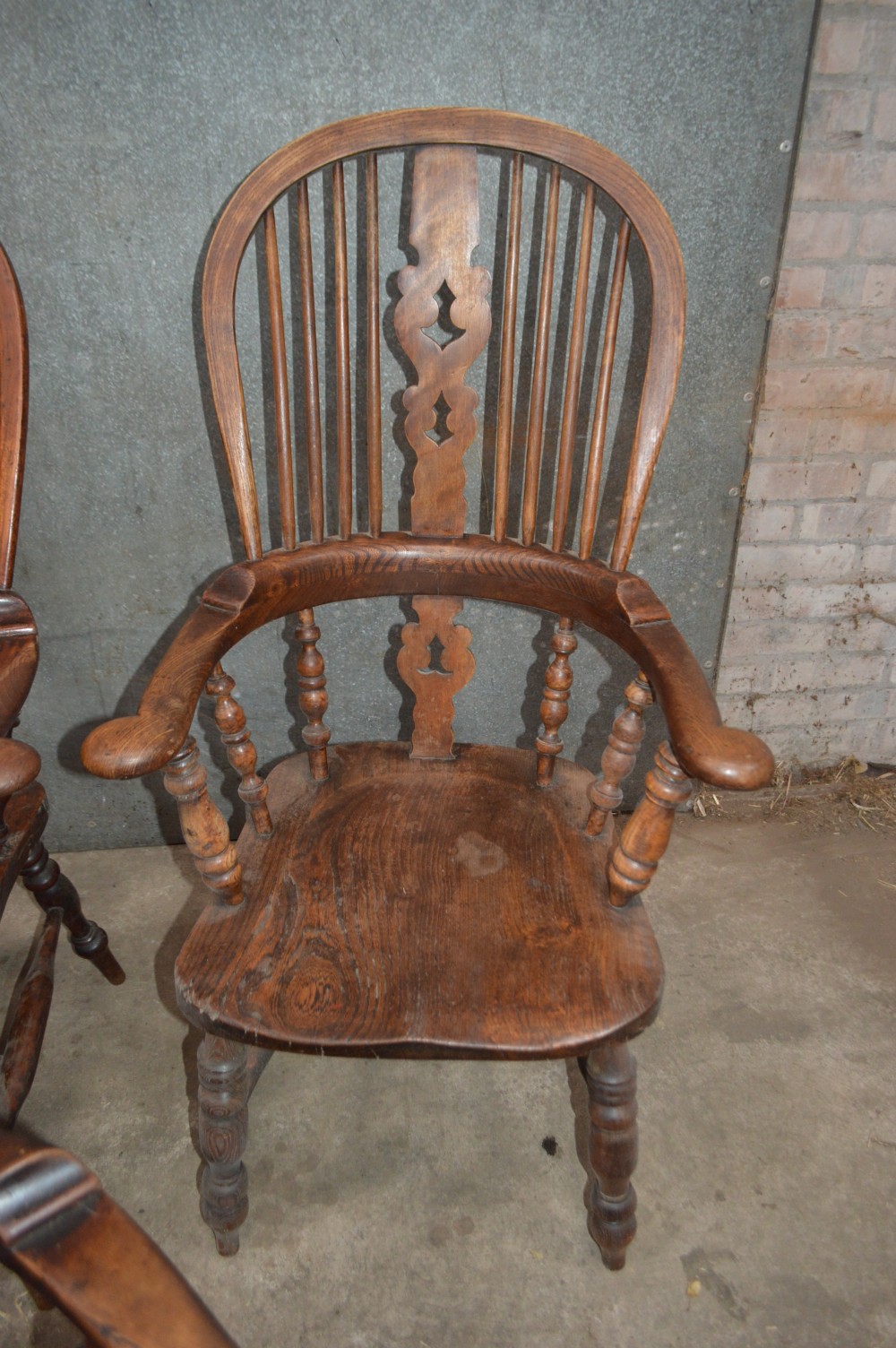 A set of six Victorian wooden Windsor armchairs featuring high hoop backs, central decorative splats, pad arms, and turned legs. View VII