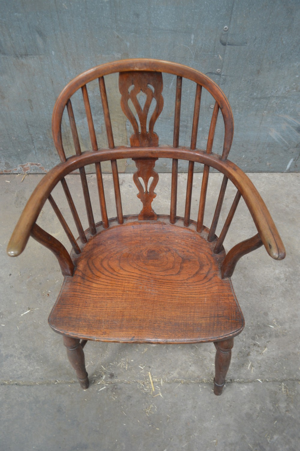 A Victorian low back Windsor armchair crafted from warm brown wood, featuring a bentwood arm bow, turned legs, and a decorative central pierced splat. View IV
