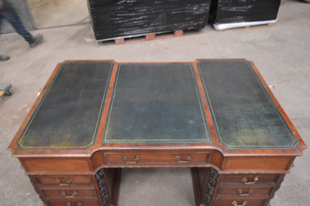 Victorian mahogany partners desk featuring double pedestals, detailed floral carvings on the corners, brass drop handles, and a leather inset top. View II