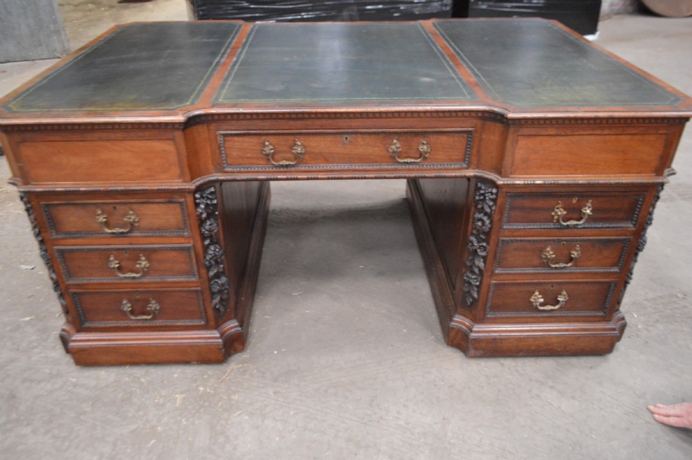 Victorian mahogany partners desk featuring double pedestals, detailed floral carvings on the corners, brass drop handles, and a leather inset top. View III