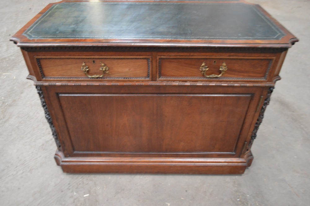 Victorian mahogany partners desk featuring double pedestals, detailed floral carvings on the corners, brass drop handles, and a leather inset top. View VII