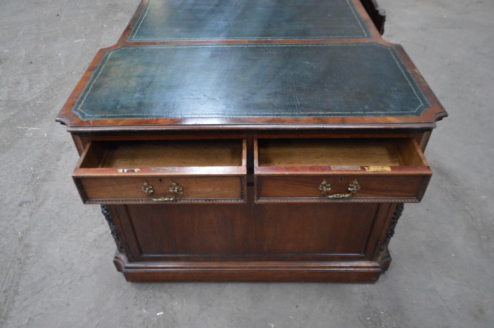 Victorian mahogany partners desk featuring double pedestals, detailed floral carvings on the corners, brass drop handles, and a leather inset top. View IX