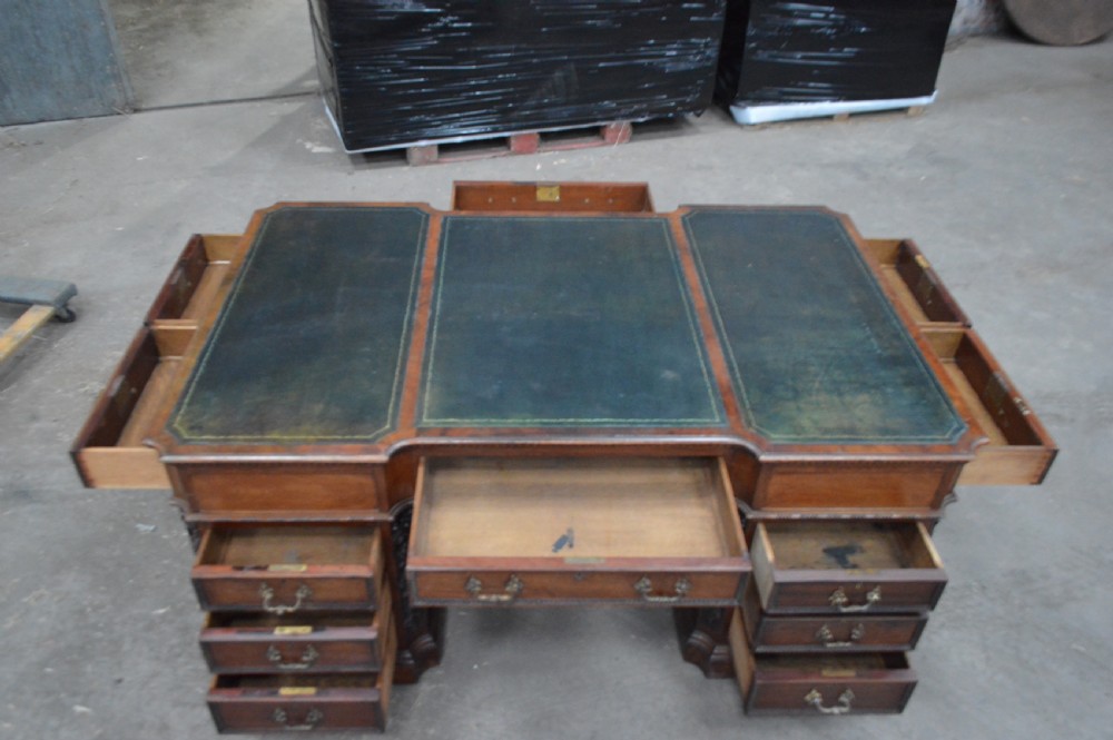 Victorian mahogany partners desk featuring double pedestals, detailed floral carvings on the corners, brass drop handles, and a leather inset top. View XI