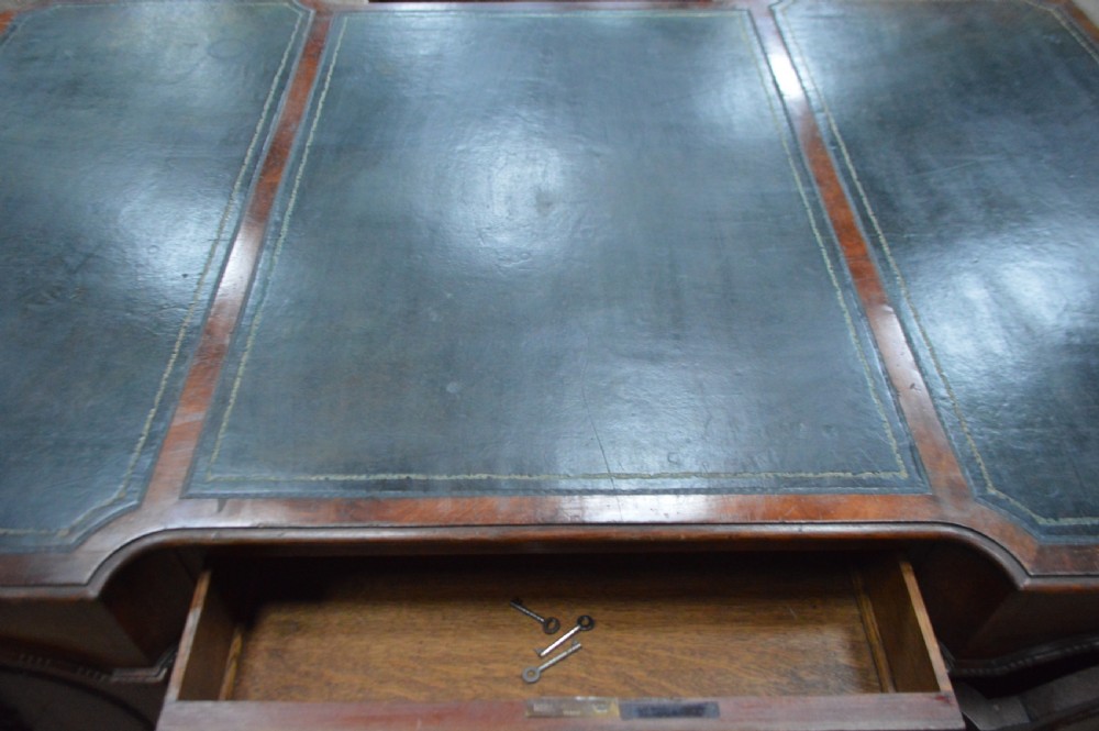 Victorian mahogany partners desk featuring double pedestals, detailed floral carvings on the corners, brass drop handles, and a leather inset top. View XV