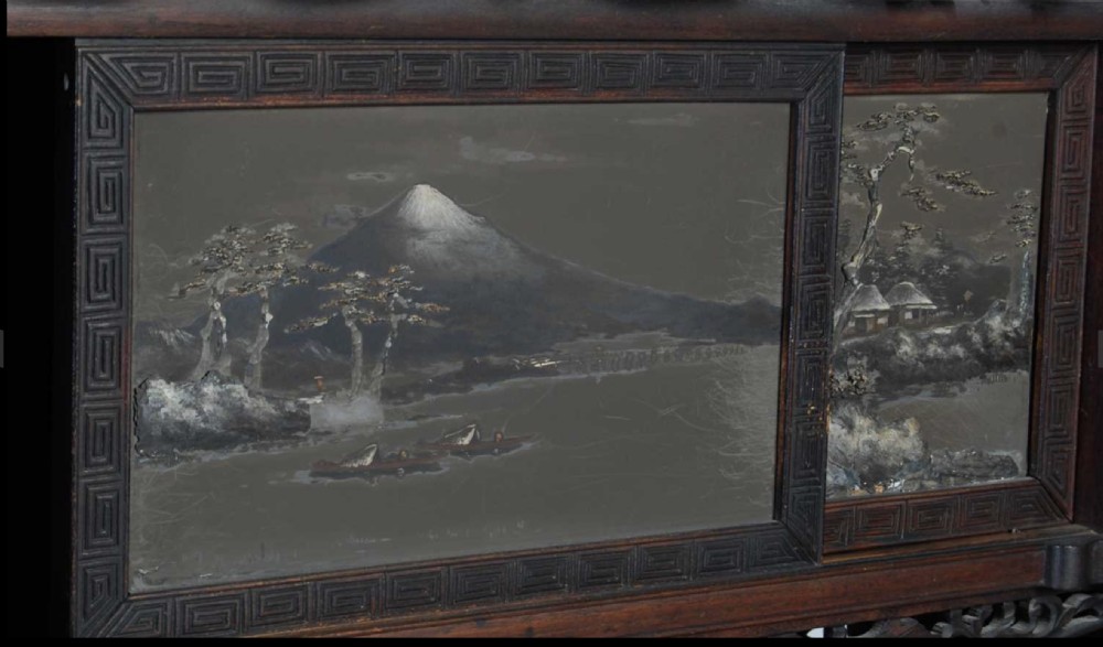 A tall dark wood Japanese Shodona cabinet featuring pierced openwork carvings, asymmetrical shelves, and painted landscape panels, mounted on a carved base. View VI