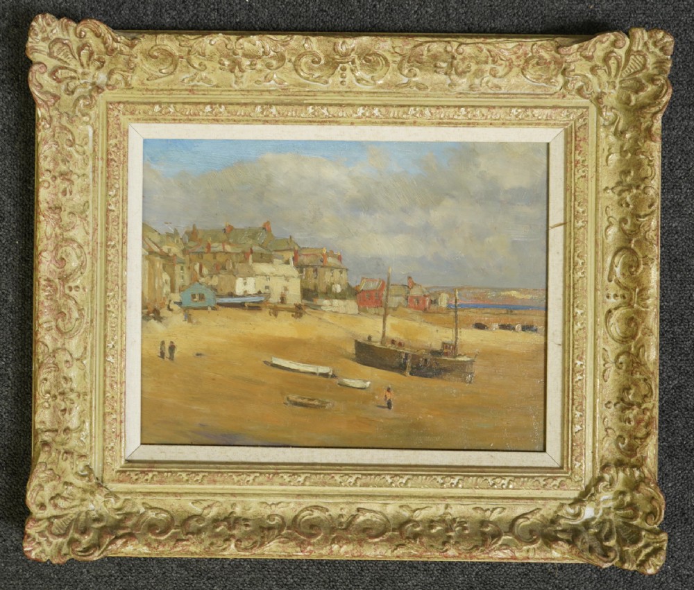 A framed oil painting depicting St Ives harbour with grounded boats on a sandy beach alongside coastal cottages under a cloudy sky.