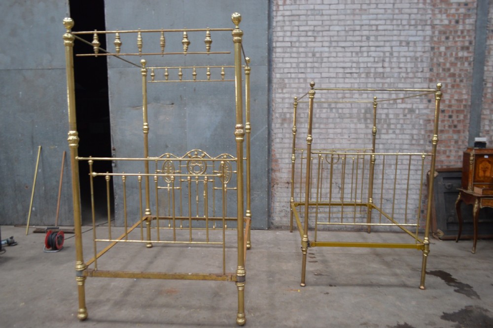 A Victorian tubular brass four poster bed frame featuring decorative spindled canopy rails, turned finials, and an ornamental central headboard motif. View IV