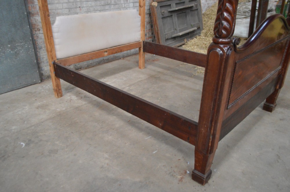 Victorian mahogany four poster bed featuring carved spiral posts, gilt finials, and an arched panelled footboard. View V
