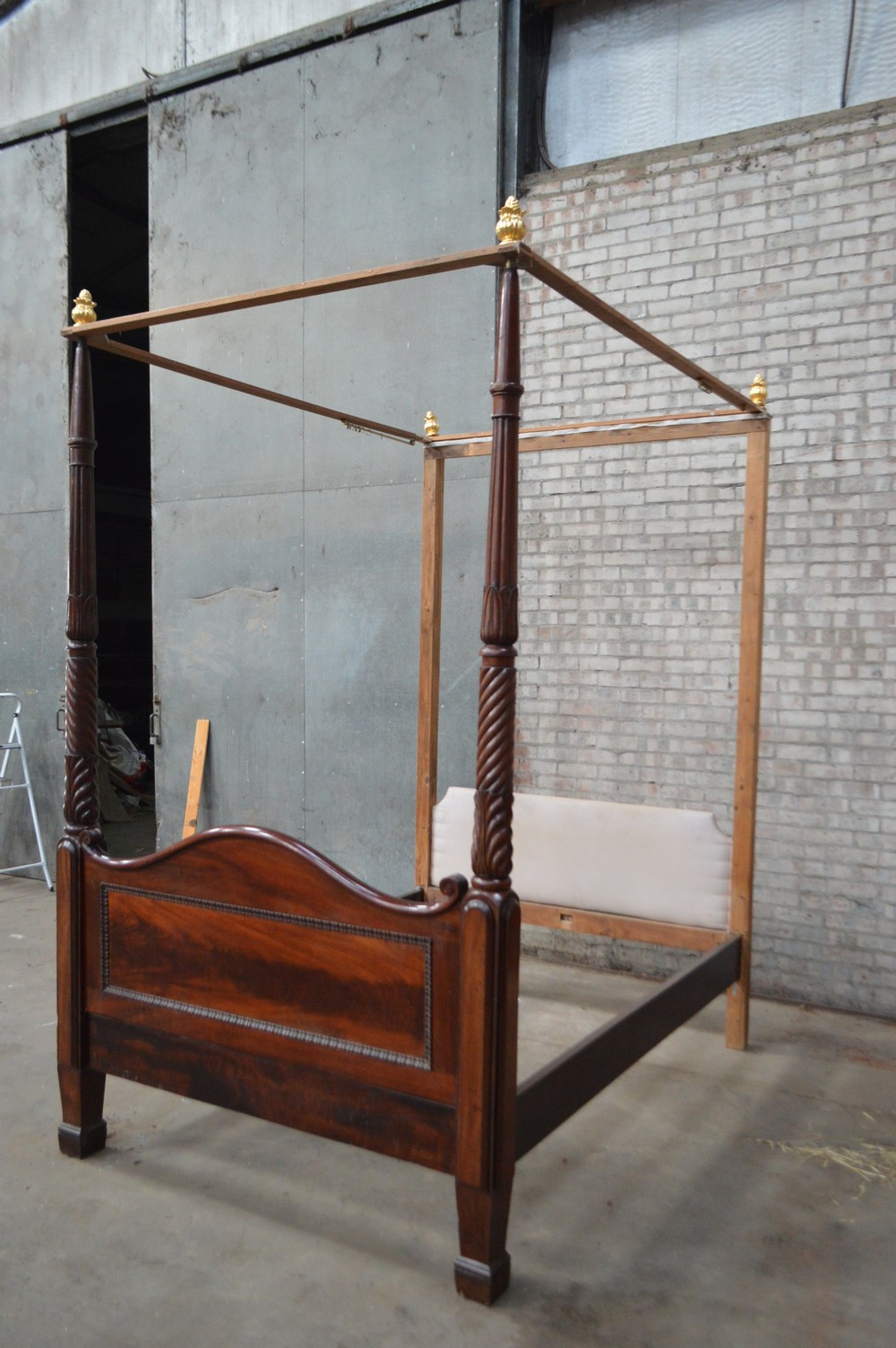 Victorian mahogany four poster bed featuring carved spiral posts, gilt finials, and an arched panelled footboard. View VI