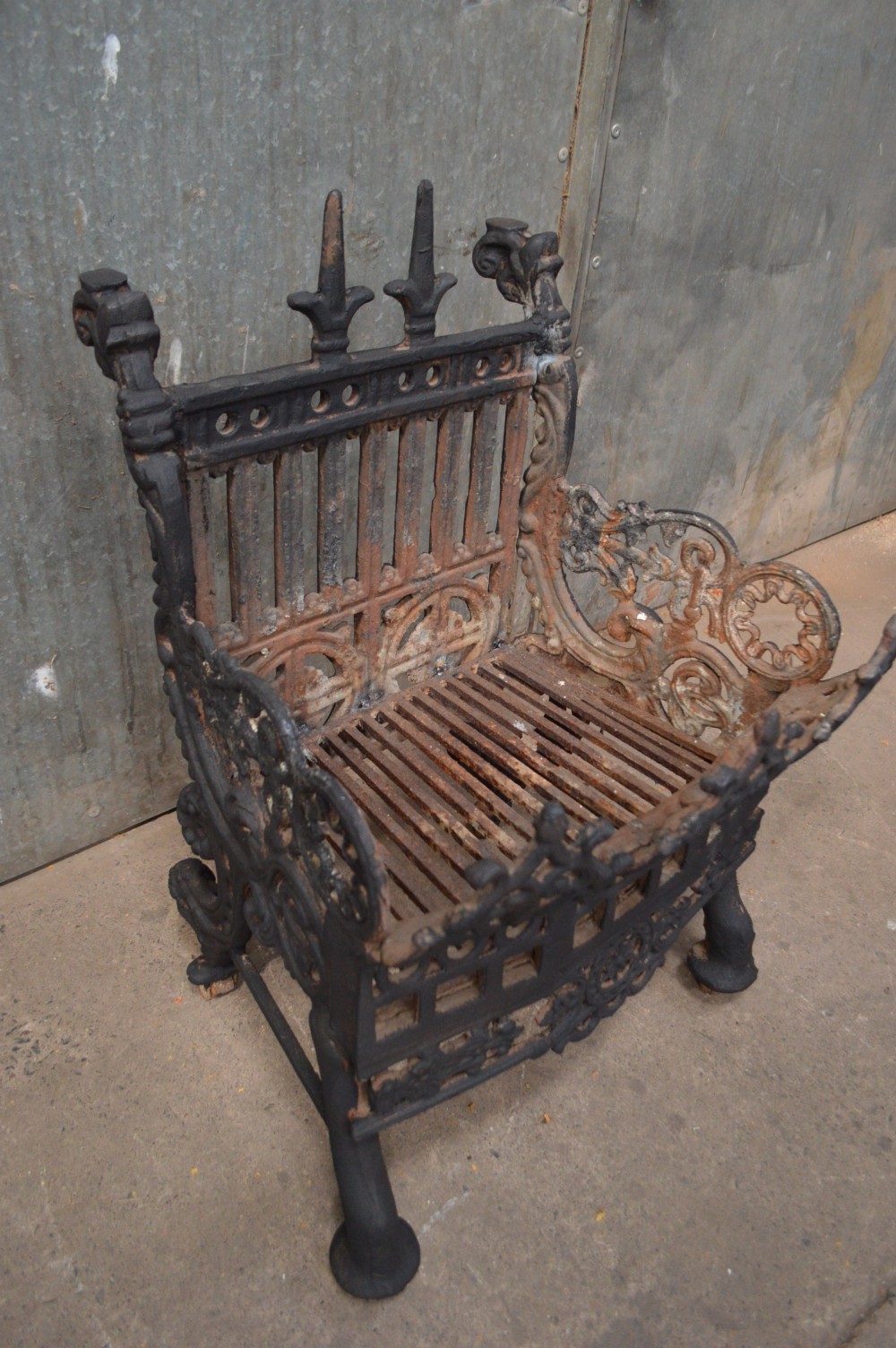 A heavy black cast iron fire basket featuring decorative Gothic style arches, finials, and an intricate fretwork front panel. View III