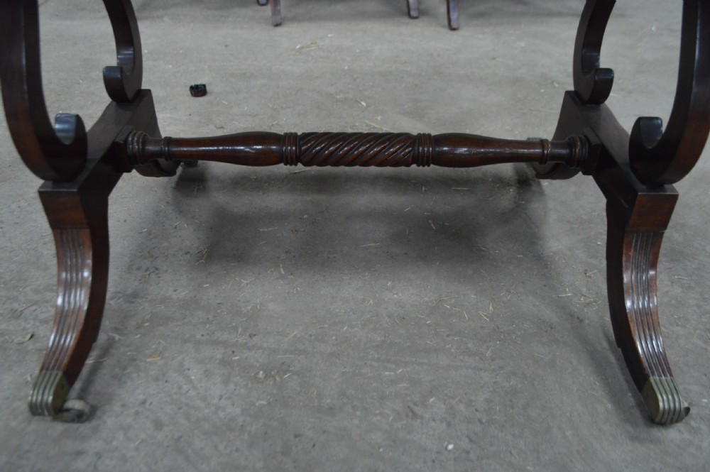 A Georgian mahogany sofa table featuring twin drop leaves, two front drawers with round wooden knobs, a turned cross-stretcher, and splayed legs ending in brass caps. View II