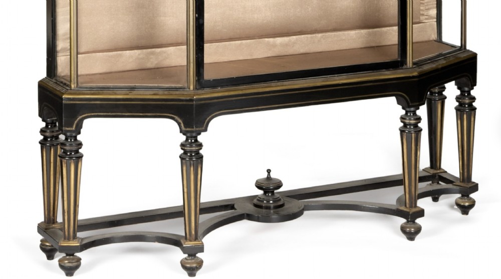 A two-tiered 19th-century ebonised and parcel-gilt vitrine cabinet with glazed doors and turned fluted legs. View II