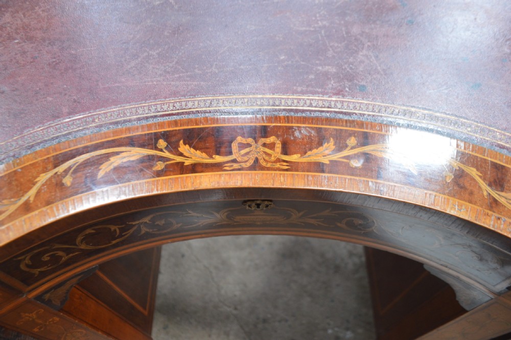 A mahogany kidney-shaped writing desk decorated with intricate marquetry urn inlays, nine drawers, and square tapered legs. View VII