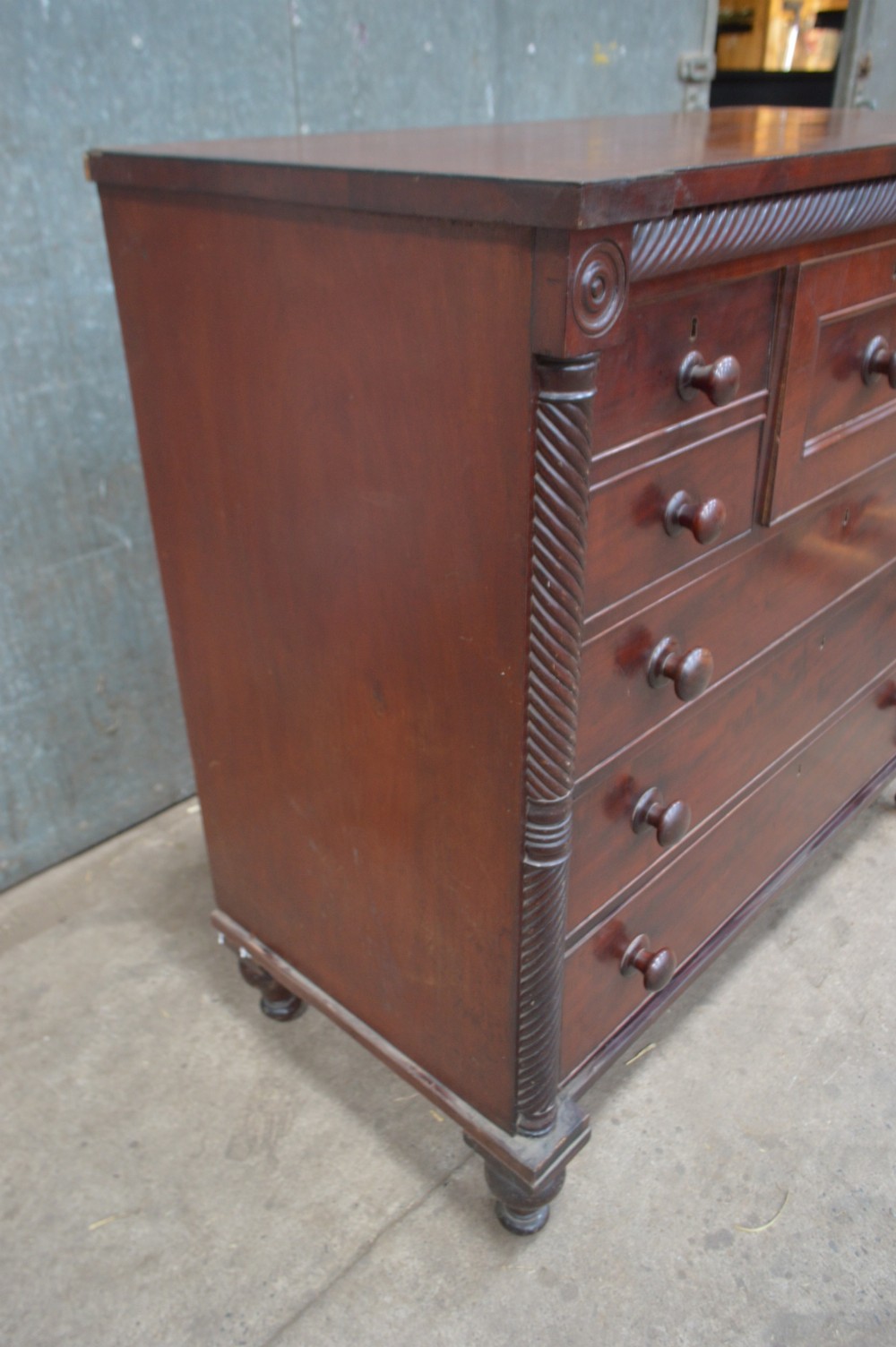 A Scottish Regency mahogany chest of drawers featuring rope-twist columns, corner rosettes, a central bonnet drawer, and turned feet. View IV