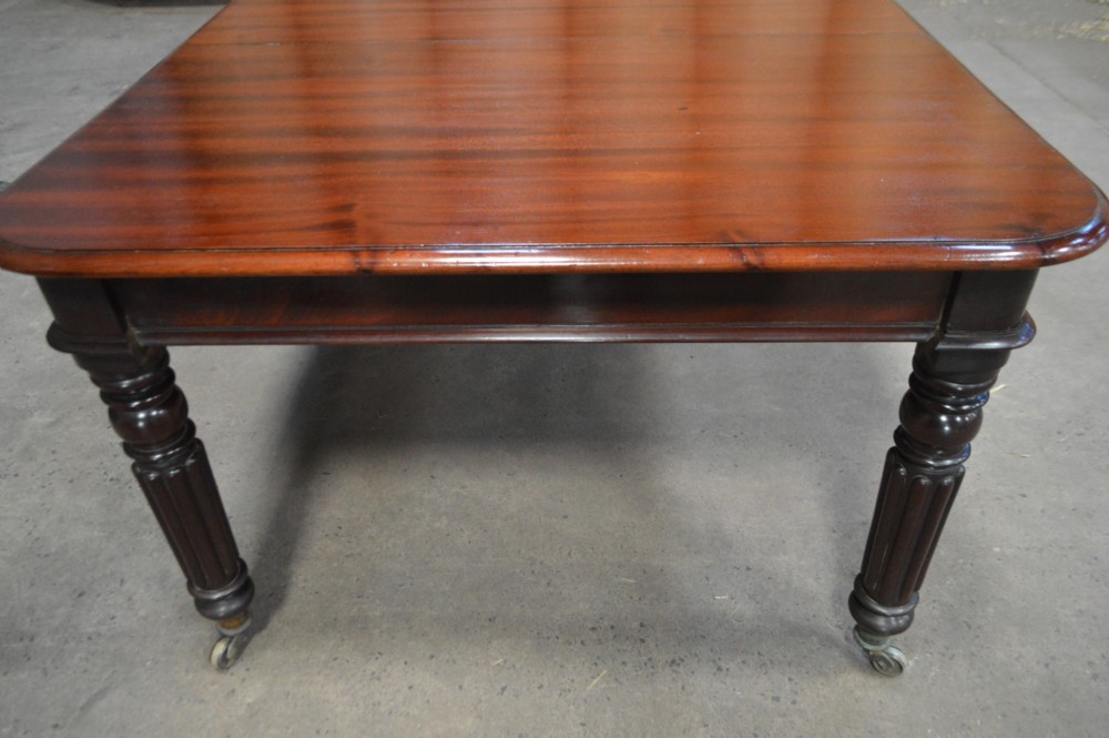 A long late Regency mahogany extending dining table featuring reeded turned legs on brass castors. View IX
